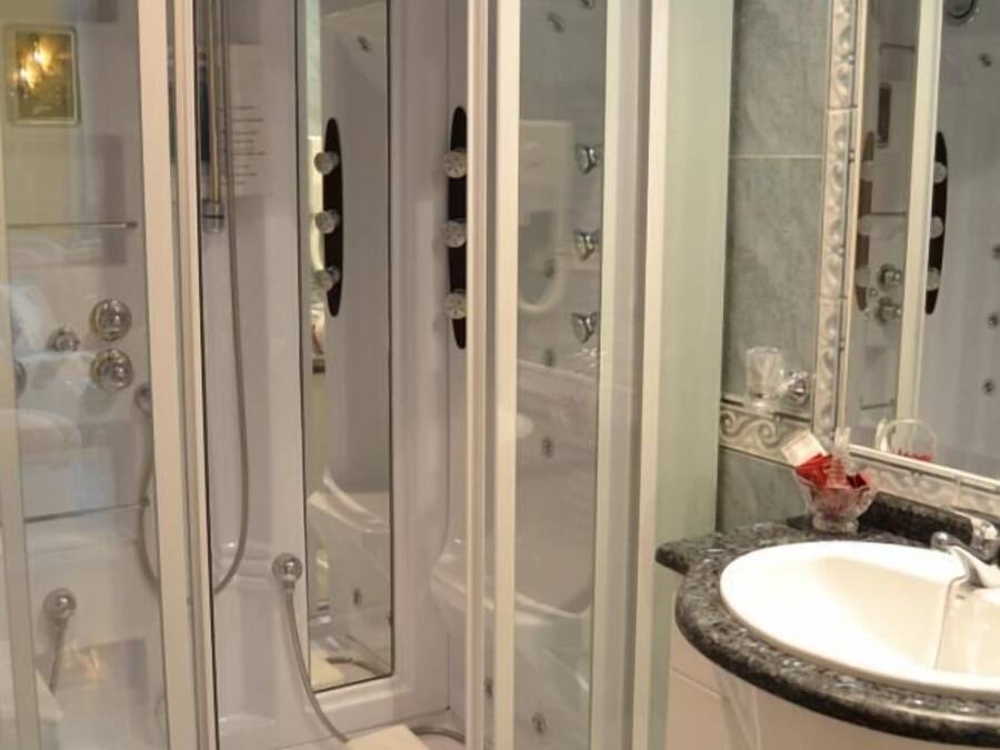Un baño moderno con ducha envuelta en vidrio, un lavabo blanco y un espejo grande.