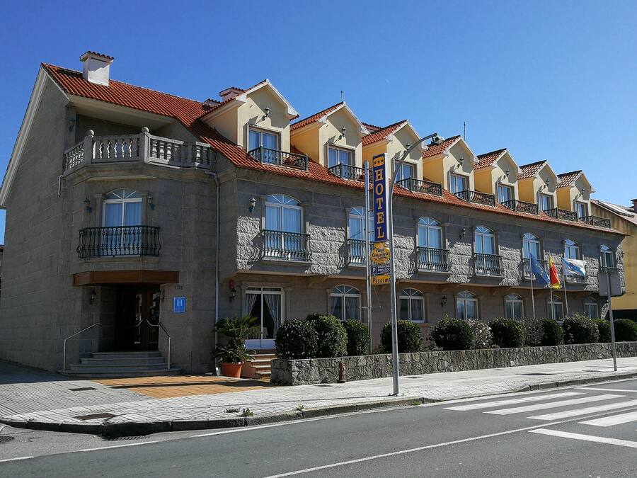 Een hotel met een stenen gevel, meerdere balkons en een dak met rode tegels.