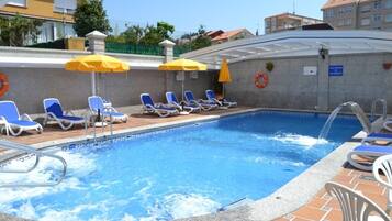 A swimming pool with blue water, surrounded by lounge chairs and yellow umbrellas.