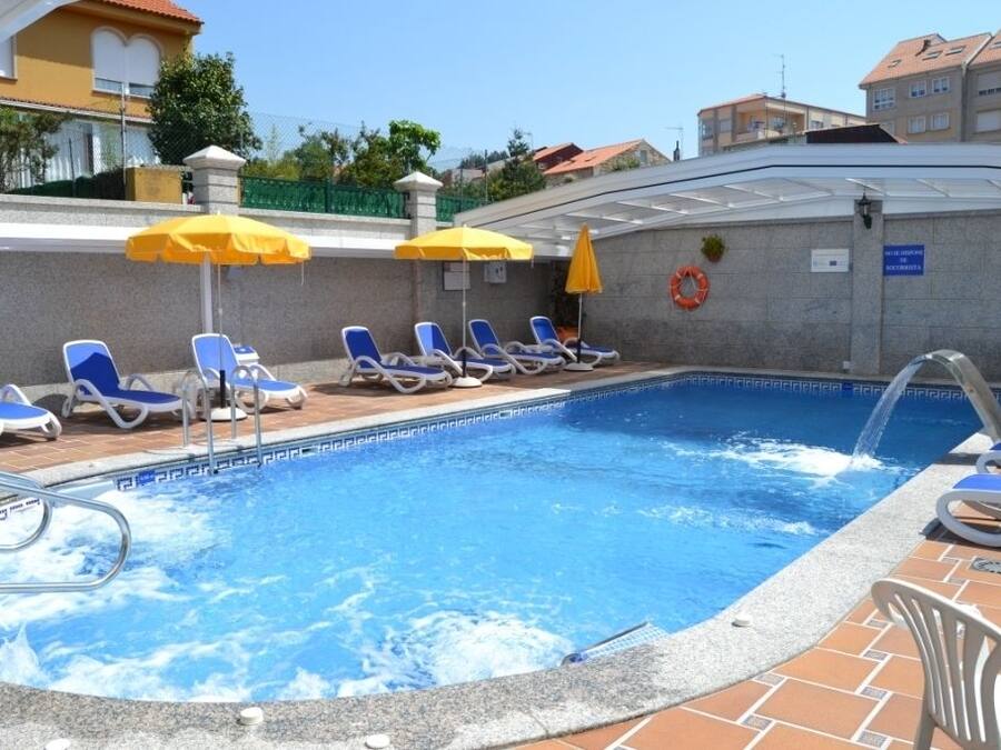 A swimming pool with blue water, surrounded by lounge chairs and yellow umbrellas.