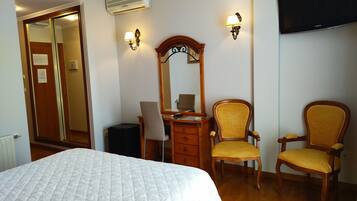 Une chambre d’hôtel équipée d’un lit, d’un bureau, de deux chaises, d’un miroir et d’un téléviseur à écran plat.