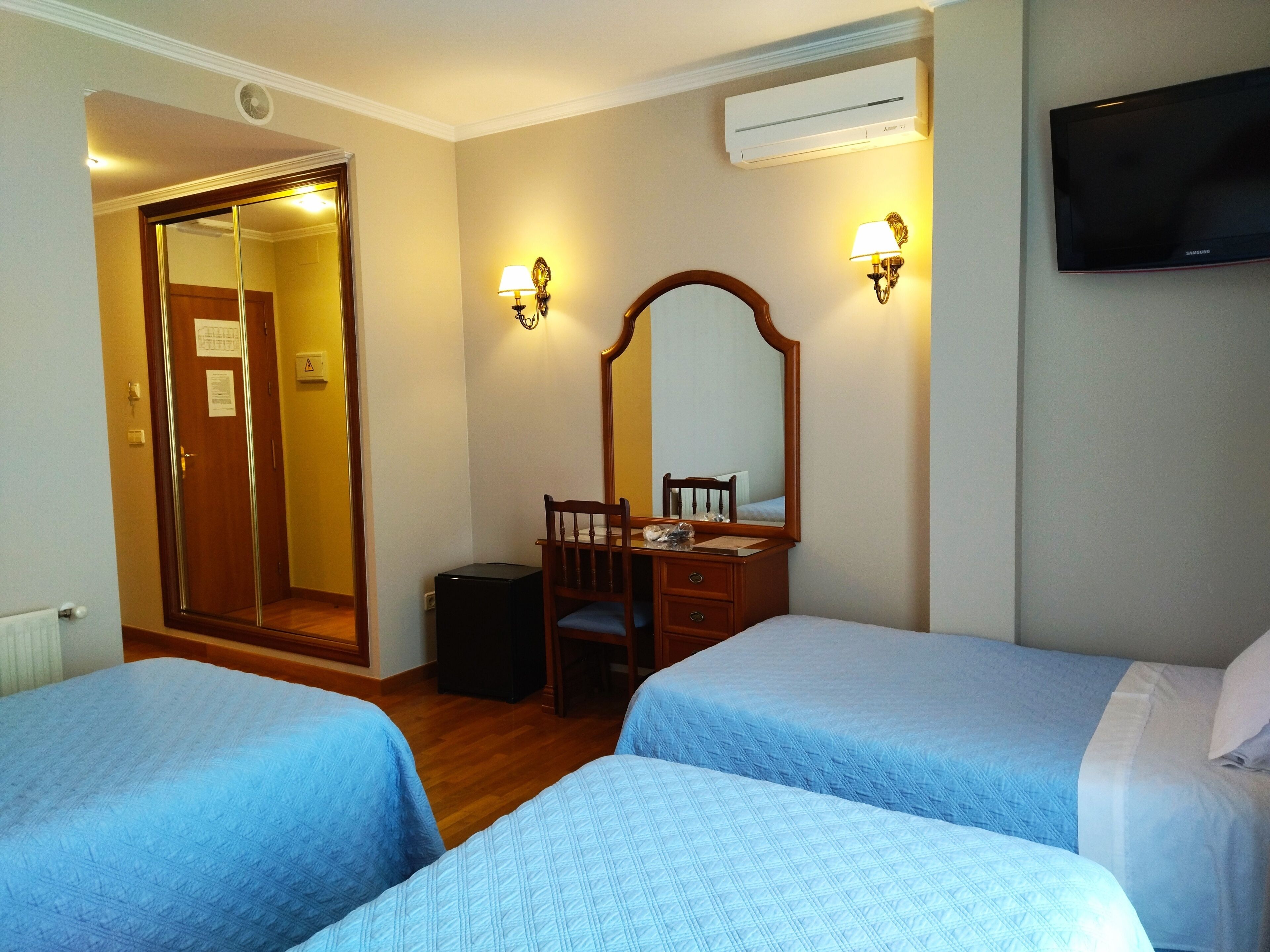 Habitación de hotel con dos camas, un aparador de madera, un espejo y un televisor de pantalla plana.