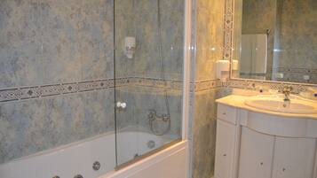 Un baño con ducha de vidrio, lavamanos y espejo.