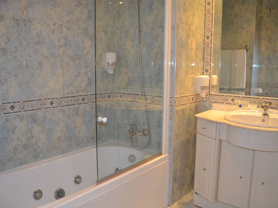 Un baño con ducha de vidrio, lavamanos y espejo.