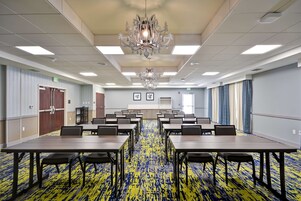A conference room with a large table, chairs, a chandelier, and a patterned carpet.