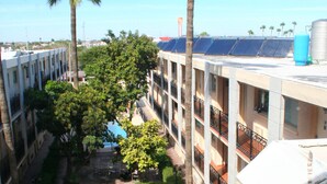 A courtyard with a fountain, palm trees, and a pool. - Hotel El Camino Inn & Suites (Reynosa)