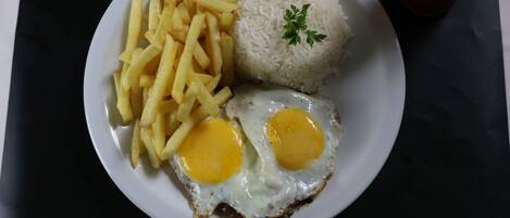 A plate with French fries, white rice, and fried eggs.
