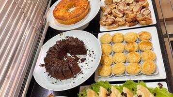 Buffet com diversos produtos de panificação, incluindo bolos, doces e pão.