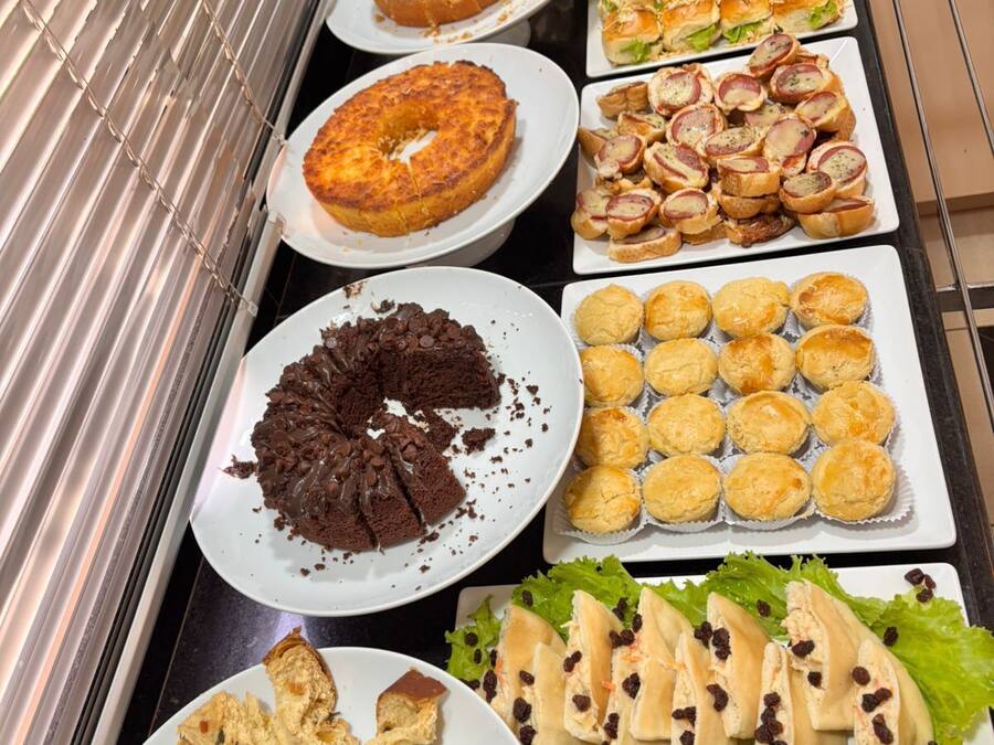 Buffet com diversos produtos de panificação, incluindo bolos, doces e pão.