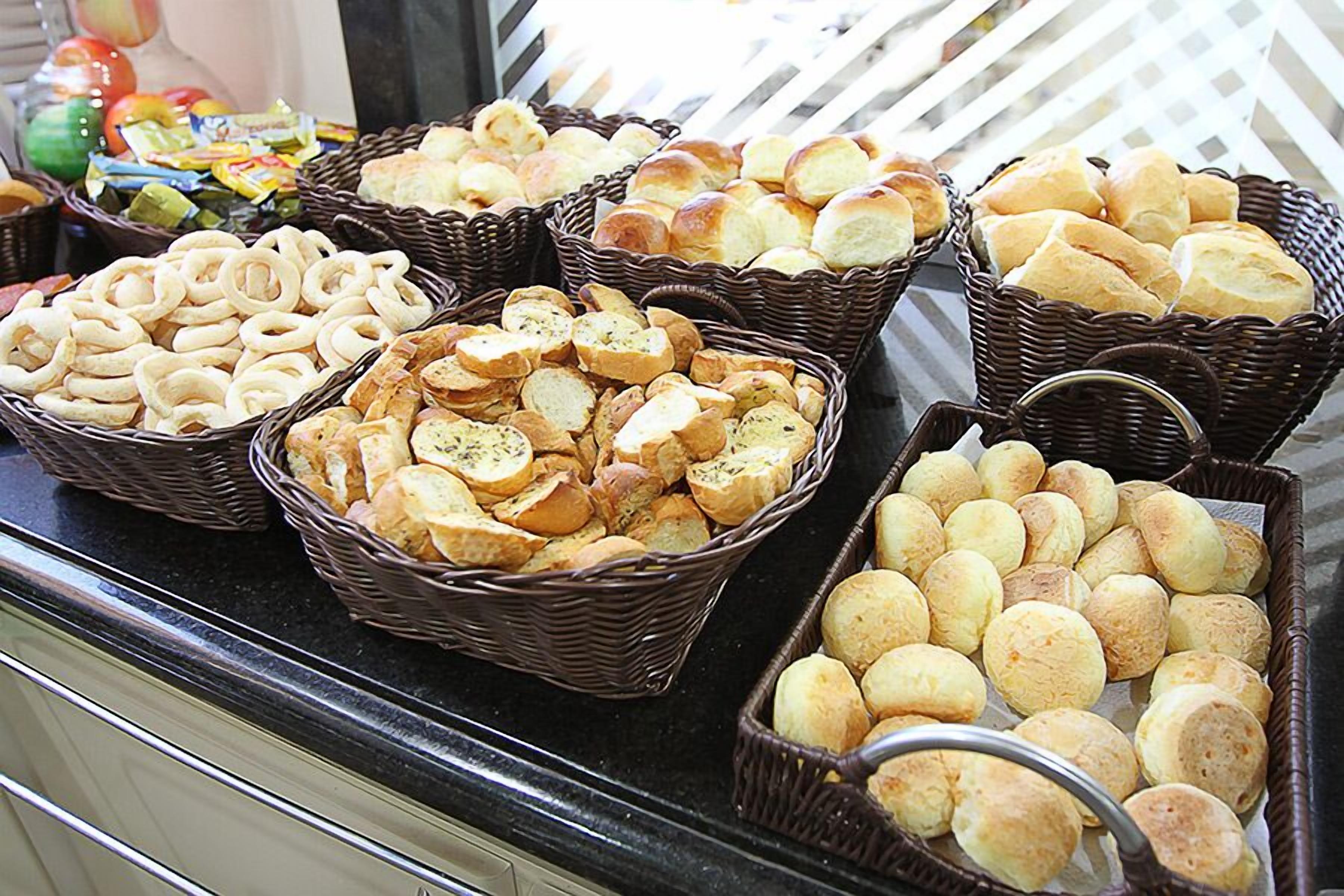 A buffet with various bread and pastries displayed in wicker baskets.