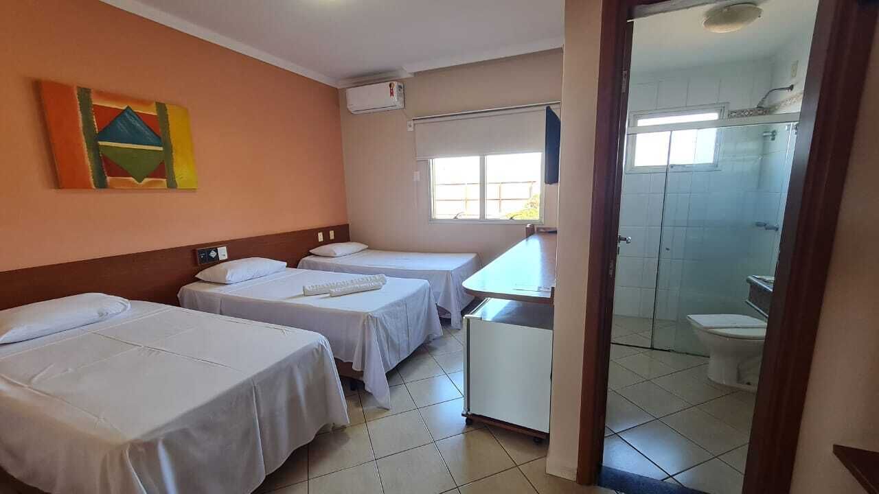 Une chambre d’hôtel avec deux lits simples, un petit bureau, une fenêtre et vue sur la salle de bain.