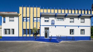 A building with a blue and yellow facade, a central entrance with a blue door, and a staircase leading to the entrance. - Hotel Lazkao  (Lazkao)