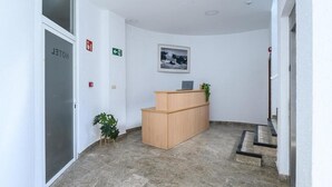 A reception area with a wooden desk, a framed picture on the wall, and a sign indicating a toilet. - Hotel Lazkao  (Lazkao)