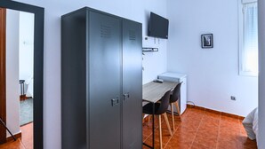 A room with a wardrobe, a desk with a chair, a television, and a framed picture on the wall. - Hotel Lazkao  (Lazkao)