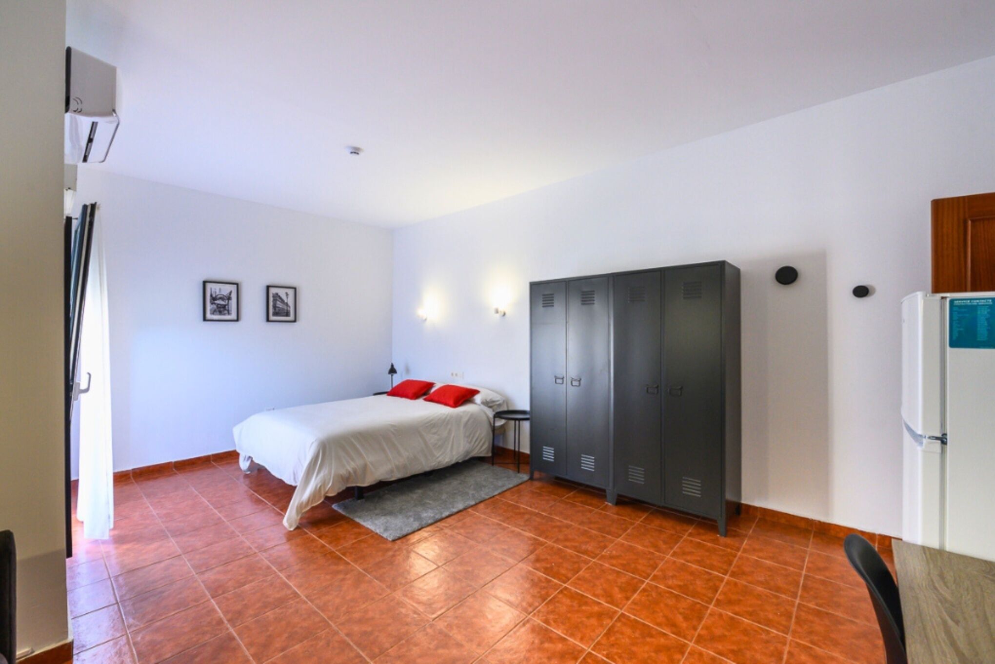 A bedroom with a bed, a wardrobe, a desk, and a chair.