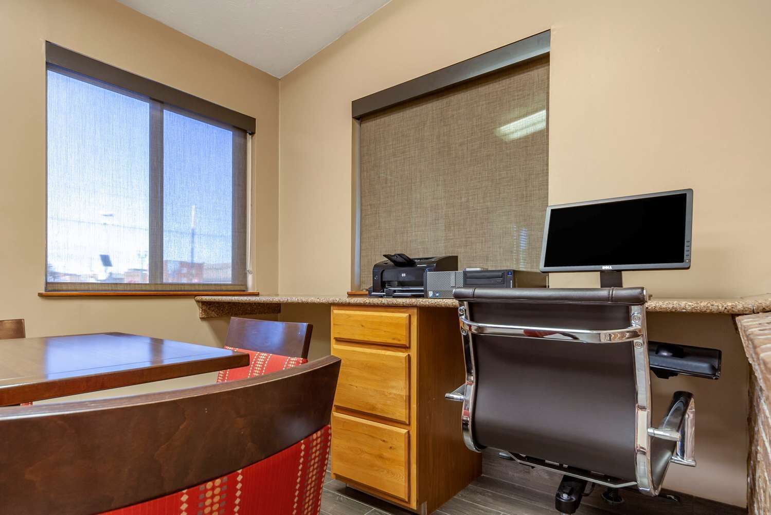 Een hotelkamer met een bureau, stoel en een groot raam.