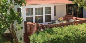 A white building with a red roof, a wooden fence, and a patio with outdoor furniture. - Thorp House Inn & Cottages (Fish Creek)