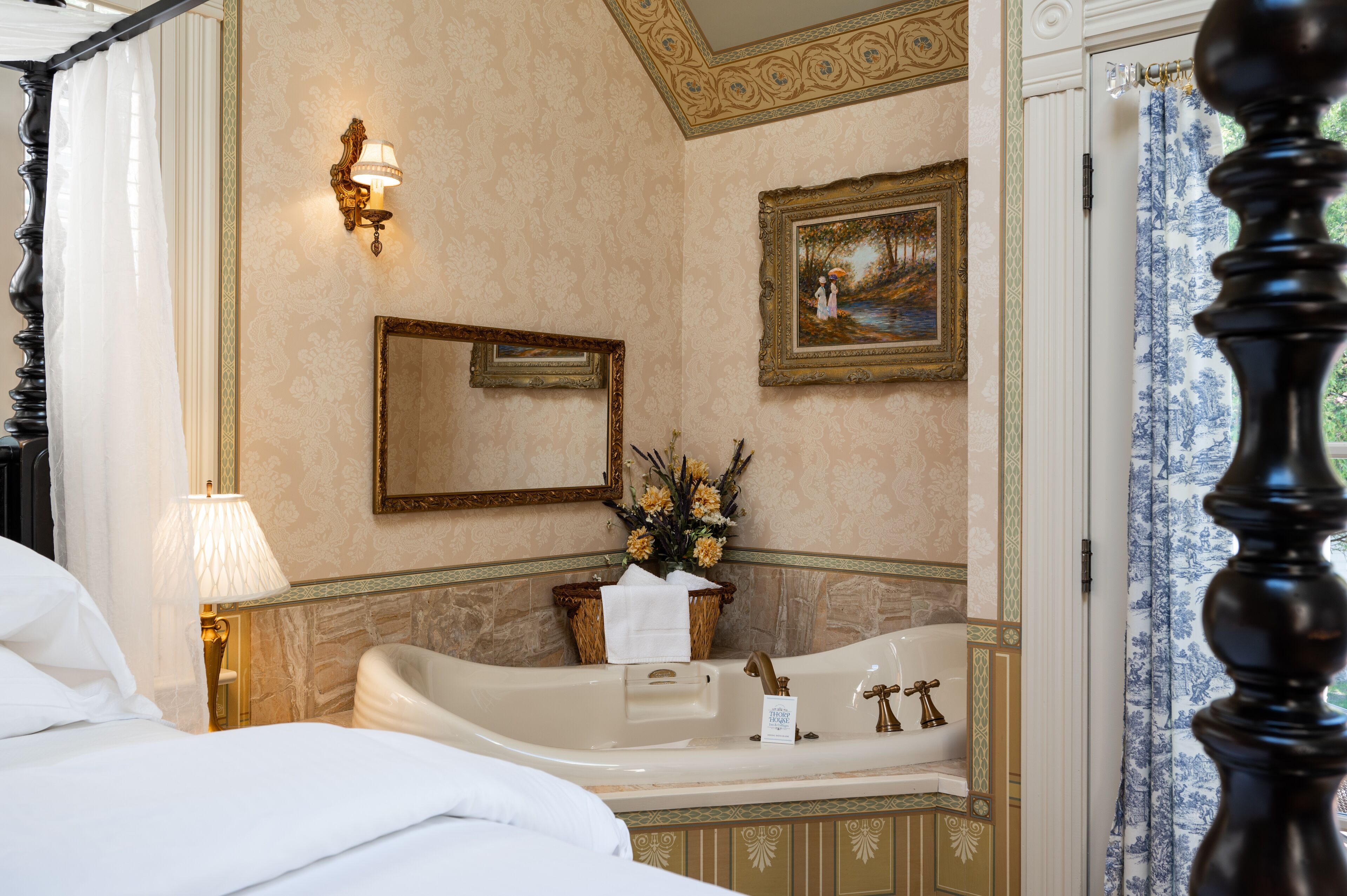 Une salle de bain luxueuse avec une grande baignoire, un miroir et un tableau encadré au mur.