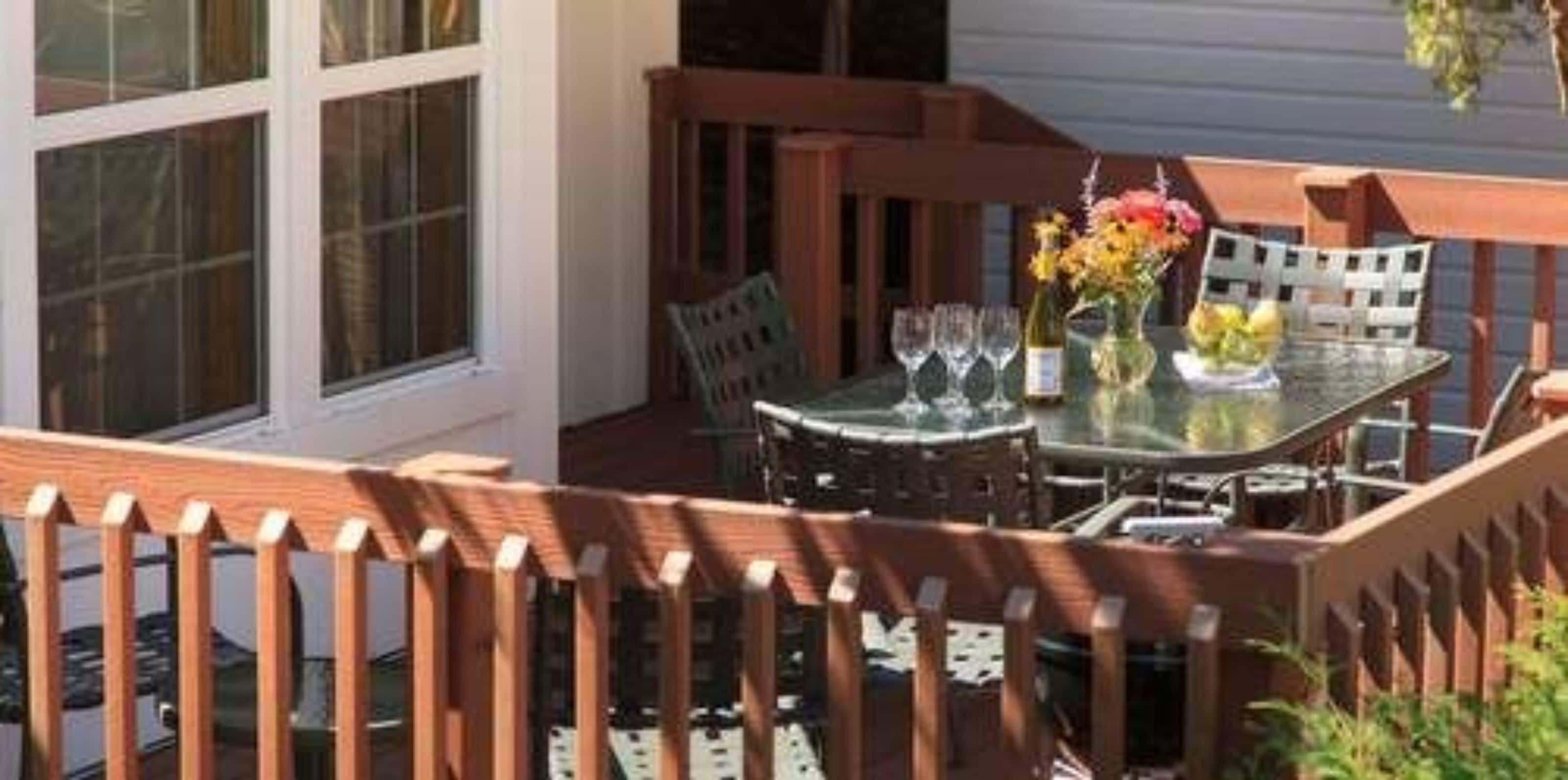 An outdoor patio with a table set for dining, surrounded by a wooden fence.