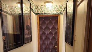 Un couloir avec une porte en bois, un tapis à motifs et des tableaux encadrés accrochés aux murs.