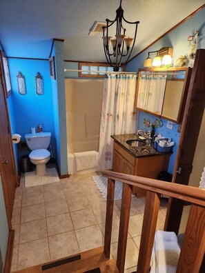 Bathroom features a toilet, sink, and shower area with a curtain.