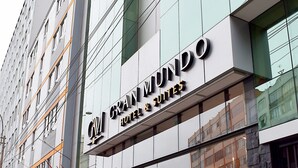 Un hotel con fachada moderna, grandes ventanales y un letrero que dice 'Gran Mundo Hotel & Suites'.