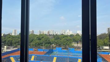 Una cancha de tenis con asientos y un paisaje urbano al fondo.