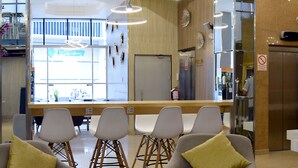 Un moderno vestíbulo de hotel con mostrador de recepción, zona de estar con sillones y una mesa de café, y un ventanal que ofrece vistas al exterior.