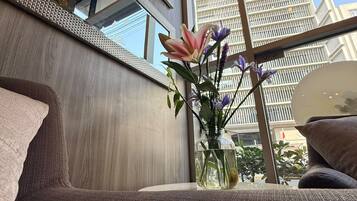 Un interior moderno con un ventanal grande, un florero con flores y un sofá.