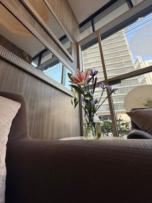 En modern inredning med ett stort fönster, en vas med blommor och en soffa.