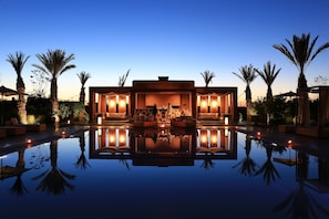 A luxurious poolside area with a reflective pool, outdoor seating, and ambient lighting. - Dar Sofil - Adults Only (Marrakech)