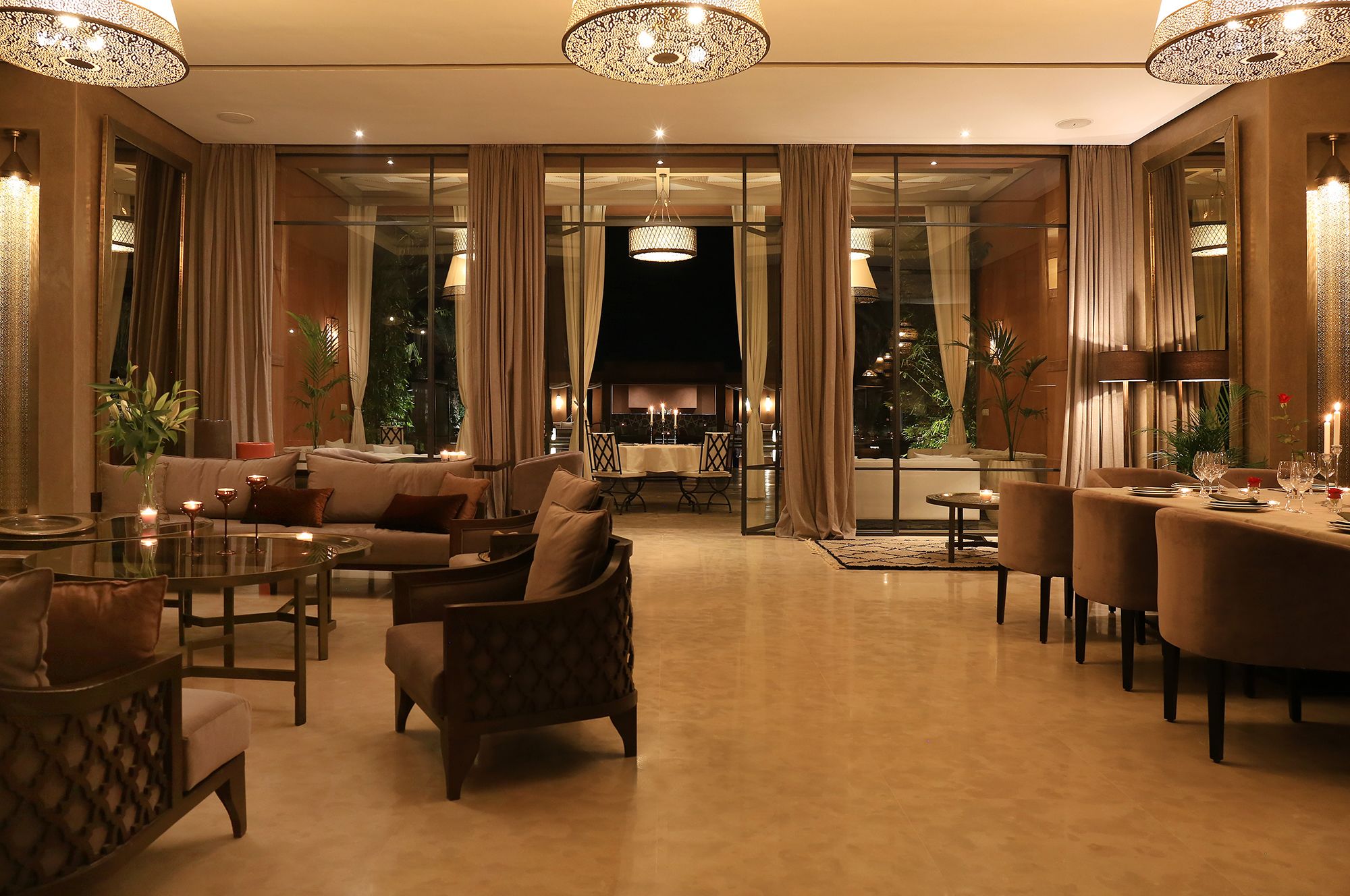 Un salon luxueux comprenant un canapé, des fauteuils et une table à manger dressée pour un repas.