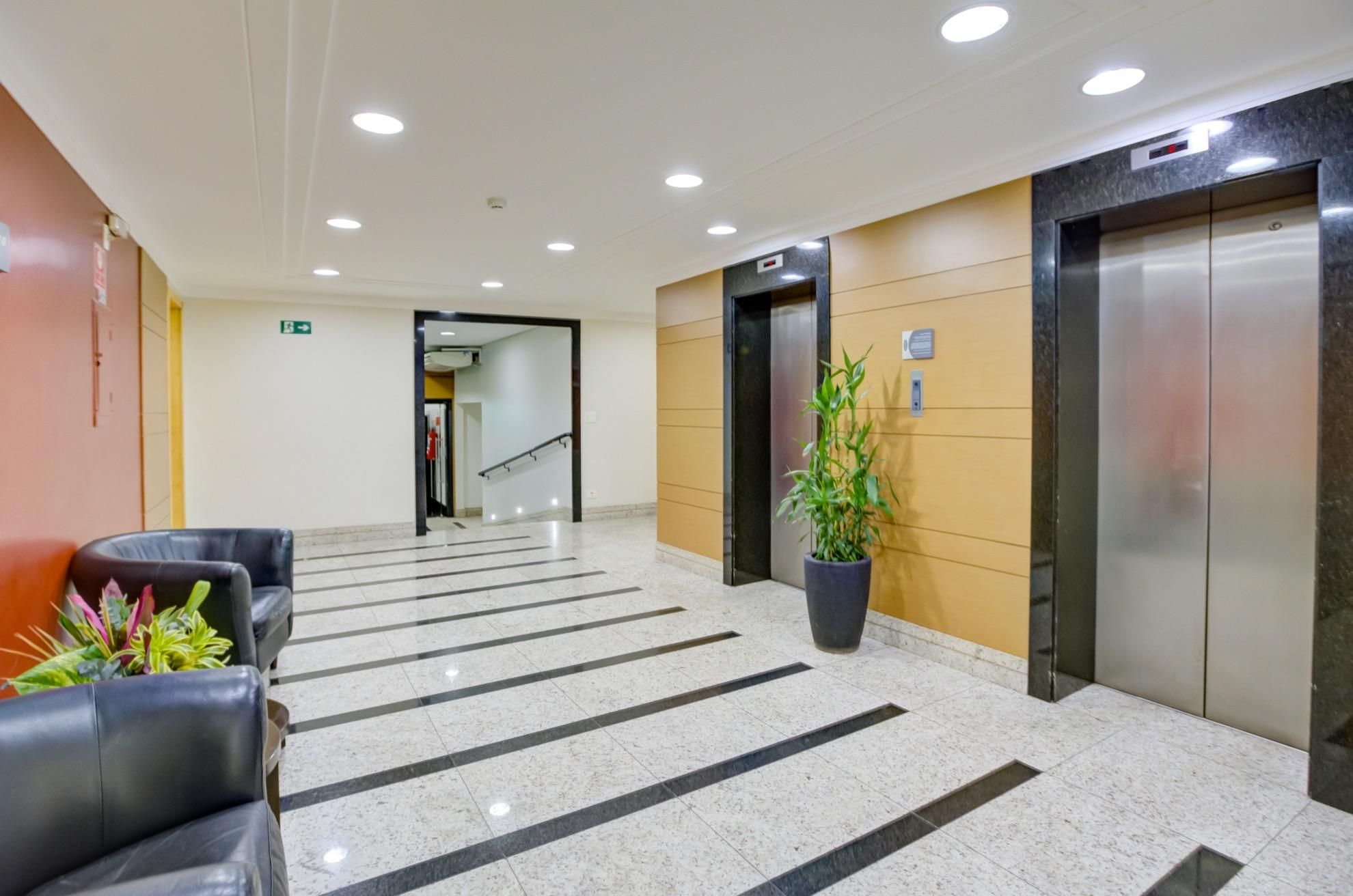 Un vestíbulo de hotel con una recepción, una escalera y dos ascensores.