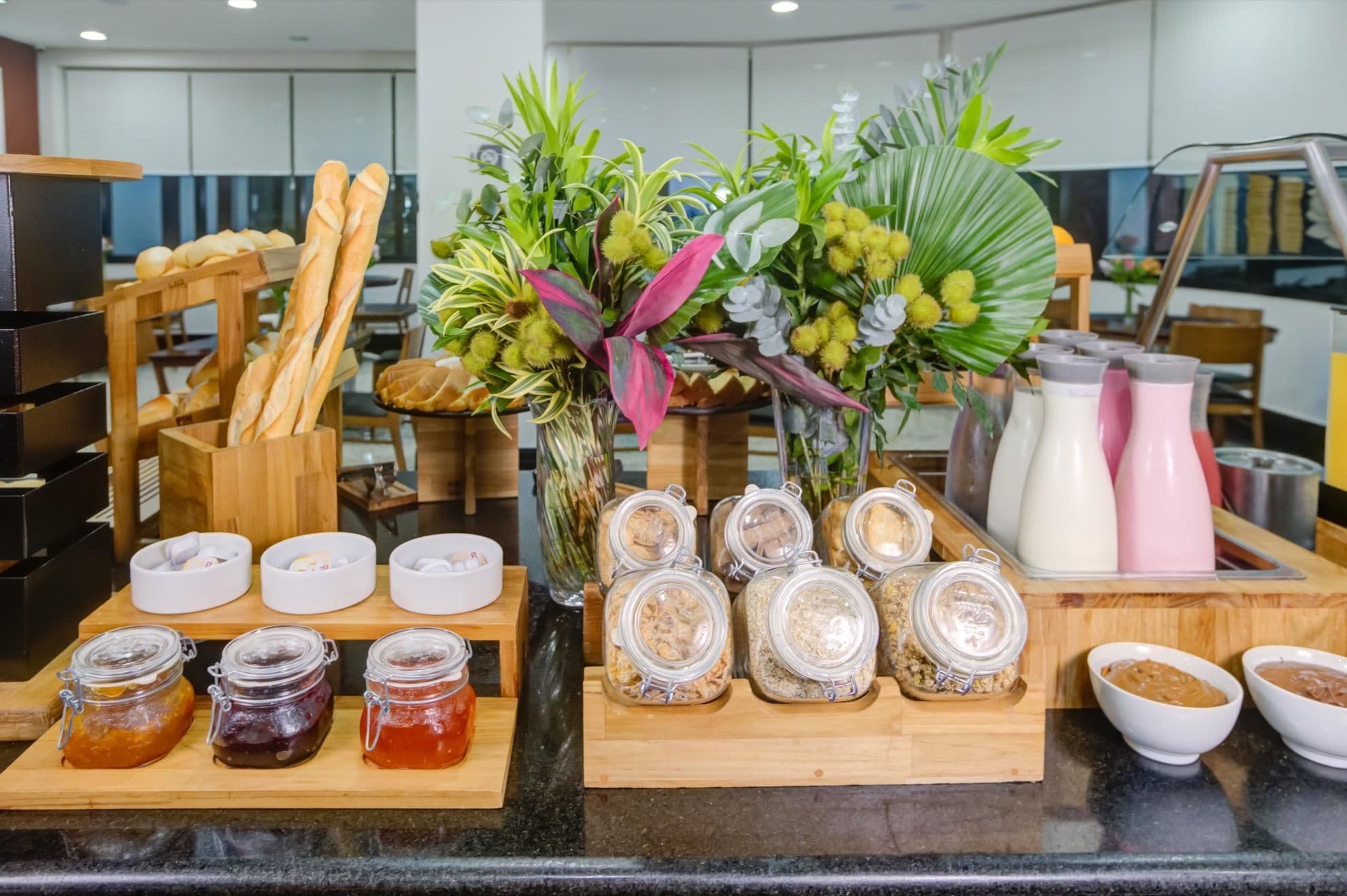 Un bufé de desayuno con pan, bollería y diferentes salsas.