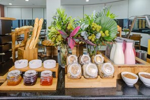 A breakfast buffet with bread, pastries, and various condiments. - Hotel Domani (Guarulhos)