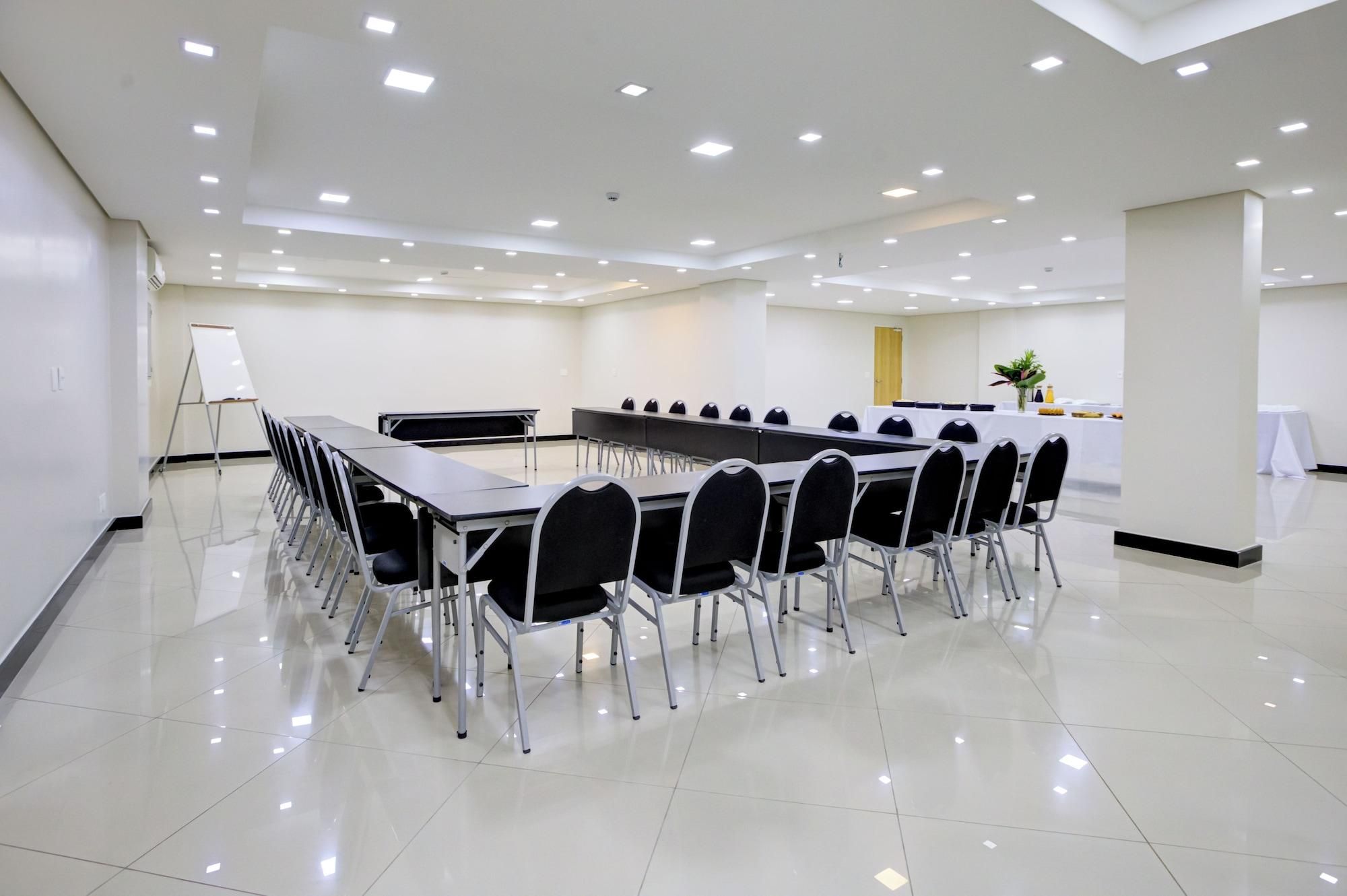 Una sala de conferencias con una larga mesa y sillas, una pizarra y una planta pequeña.