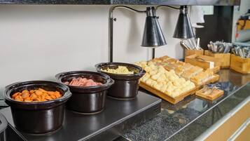 A buffet setup with various food items in black containers on a countertop.