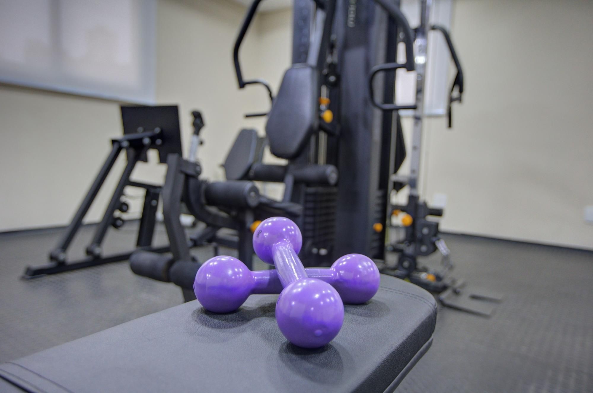 Un gimnasio con equipamiento de ejercicio, incluyendo pesas y un banco.