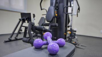 Un gimnasio con equipamiento de ejercicio, incluyendo pesas y un banco.