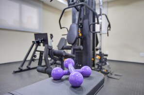 A gym with exercise equipment, including a bench and dumbbells. - Hotel Domani (Guarulhos)
