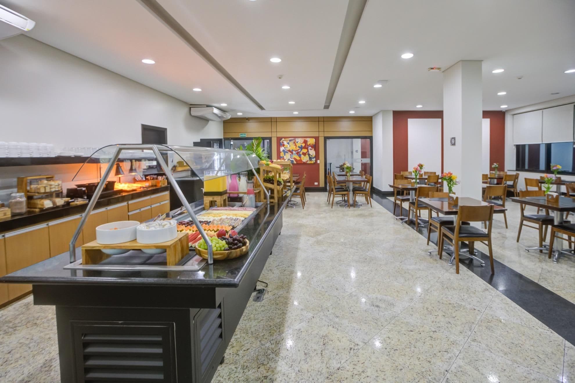 Un área de bufé con diversos alimentos, un espacio de comedor con mesas y sillas, y una decoración interior moderna.