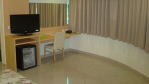 Una habitación de hotel con escritorio, silla, televisor y un refrigerador pequeño.