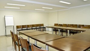 A conference room with a long table and chairs, a whiteboard, and ceiling lights.