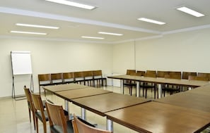 A conference room with a long table and chairs, a whiteboard, and ceiling lights. - Hotel Domani (Guarulhos)