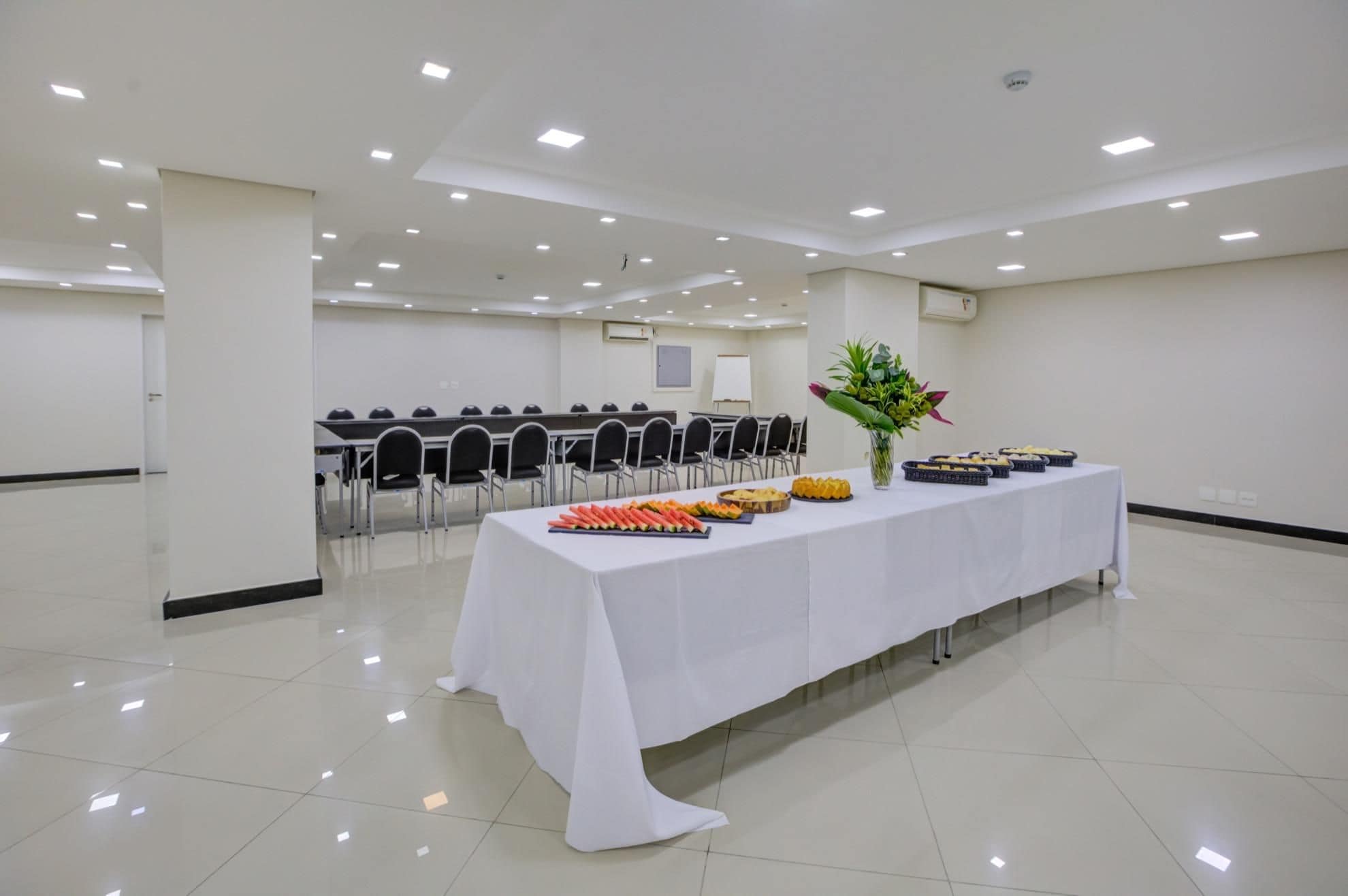 A conference room with a long table set for a buffet, chairs arranged in rows, and a whiteboard in the background.