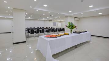 A conference room with a long table set for a buffet, chairs arranged in rows, and a whiteboard in the background.