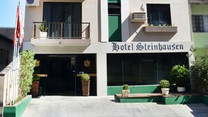 Un hôtel à plusieurs étages, doté de balcons, de climatiseurs et d’une bande verticale verte sur sa façade.