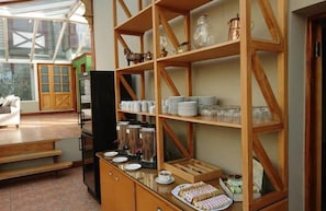 Un espace buffet pour le petit-déjeuner, avec des étagères en bois, des thermos de café et une variété d'aliments pour le petit-déjeuner.