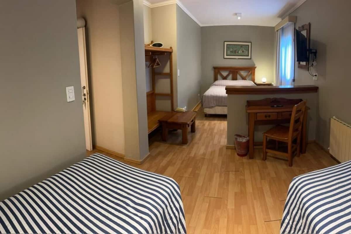 Ein Zimmer mit zwei Betten, einem Schreibtisch, einem Stuhl, einem Heizkörper und einem Fernseher.