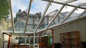 Een ruime kamer met een groot dakvenster, houten meubels en uitzicht op omliggende huizen.